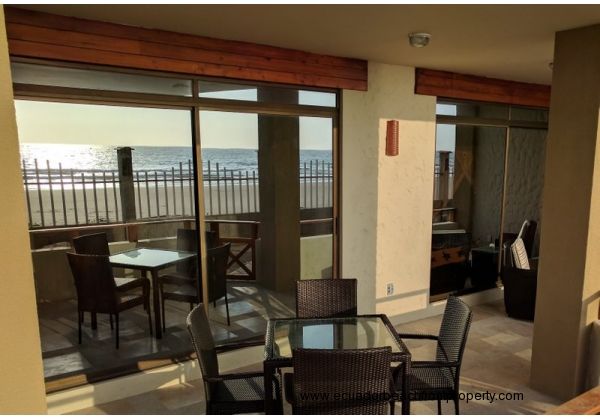 Spacious beachfront patio with dining table and chairs plus two comfy chairs with ottomans