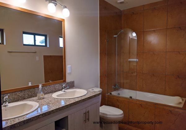 Full bath with double sinks and a bath tub.